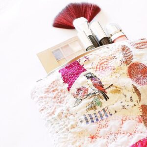 Pink embroidered toiletry bag with a bird
